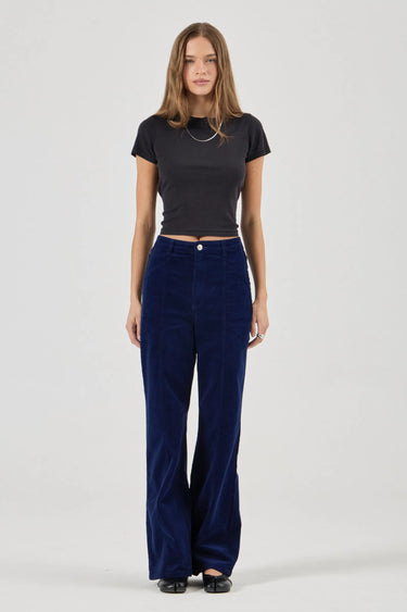 Woman wearing a black top and blue velvet pants on a white background