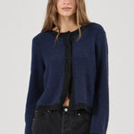 Woman wearing a blue cardigan over a black shirt and pants on a white background