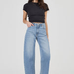 Woman wearing blue jeans and a black top on a white background