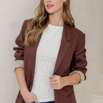 Woman wearing a brown jacket, white shirt, blue jeans