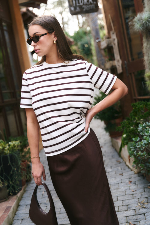 model wears a white and brown stripe t-shirt with a brown maxi skirt