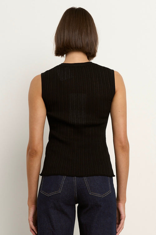 model wears a black high neck tank top with dark blue jeans