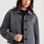 Woman wearing a gray jacket with black buttons on a white background