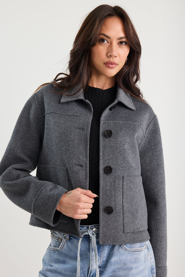 Woman wearing a gray jacket with black buttons on a white background