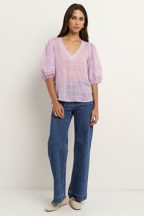 model wears a purple linen blouse with dark blue jeans