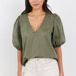 Woman wearing an olive green blouse with puff sleeves on a white background