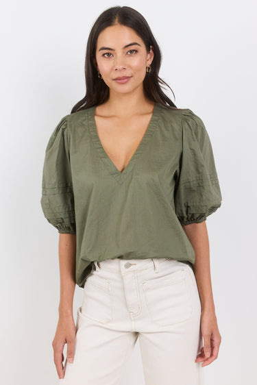 Woman wearing an olive green blouse with puff sleeves on a white background