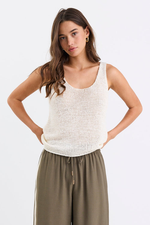 Woman wears a white natural knit top and khaki pants