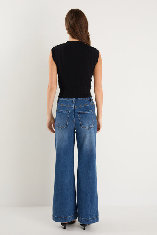 Model wears a black rib knit top with dark blue jeans