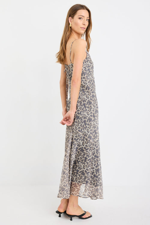 Woman wearing a leopard print strappy maxi dress in lightweight georgette with a bias cut and flowing silhouette.
