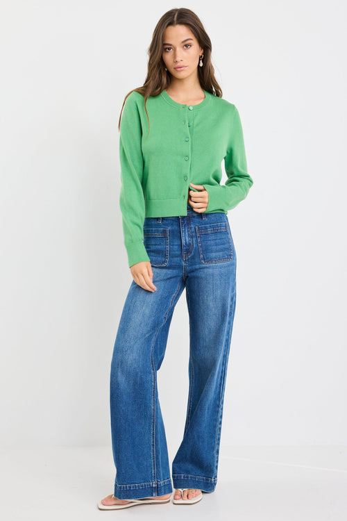 Woman wearing an apple green crewneck cardigan with long sleeves and button-front closure, styled with blue jeans.