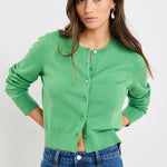 Woman wearing an apple green crewneck cardigan with long sleeves and button-front closure, styled with blue jeans.