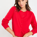 Woman wearing a cherry red crewneck cardigan with long sleeves and button-front closure, styled with denim jeans.
