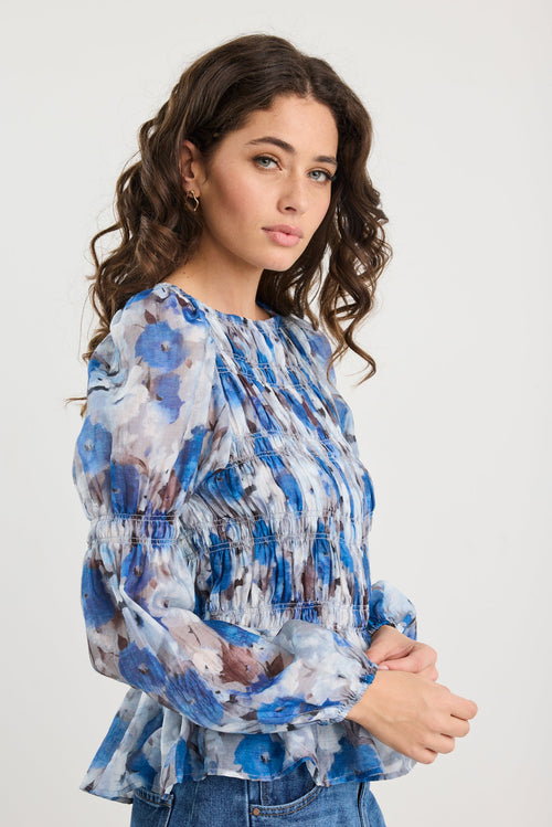 Woman wearing a blue floral blouse against a white background
