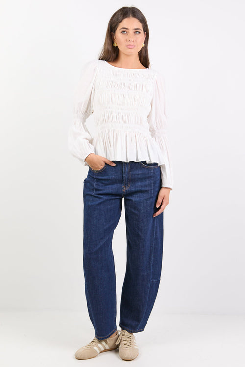 Woman wearing a white top and blue jeans on a white background