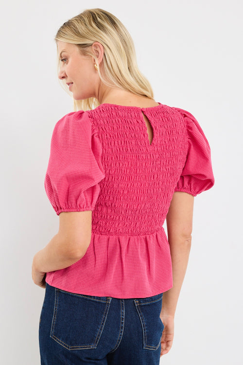 model wears a pink gingham puff sleeve top with dark blue jeans