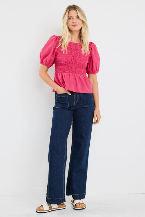 model wears a pink gingham puff sleeve top with dark blue jeans
