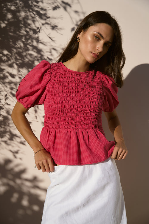 model wearing raspberry shirred top