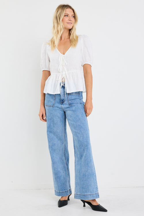 model wears a white linen puff sleeve top and light blue