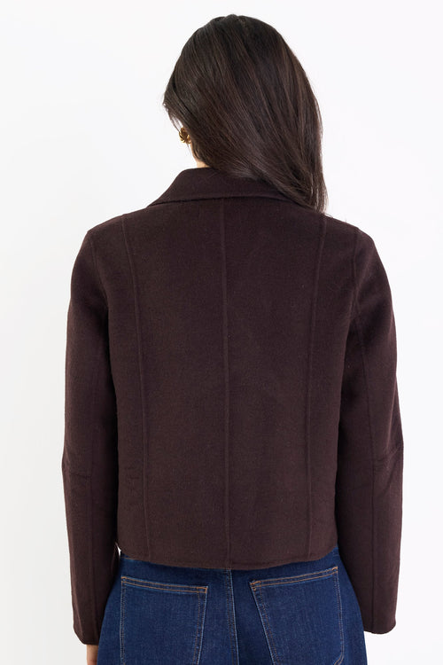 Person wearing a brown jacket and blue jeans on a white background