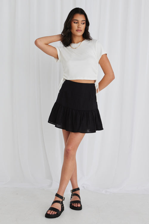 model in black mini skirt and white top and black sandals