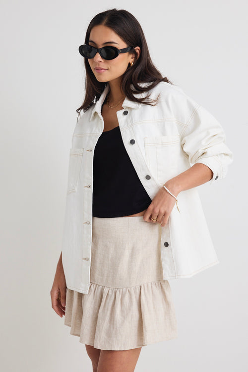 Model wears a ivory white denim jacket with front pockets and button up