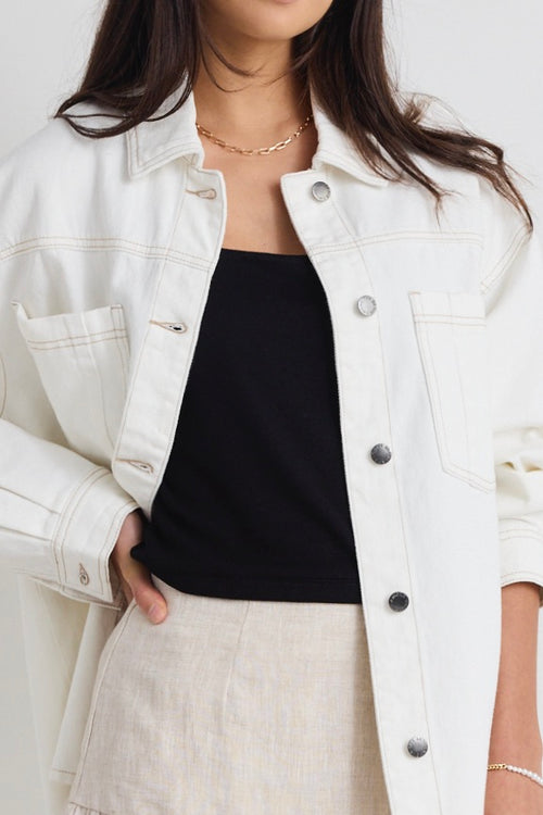 Model wears a ivory white denim jacket with front pockets and button up