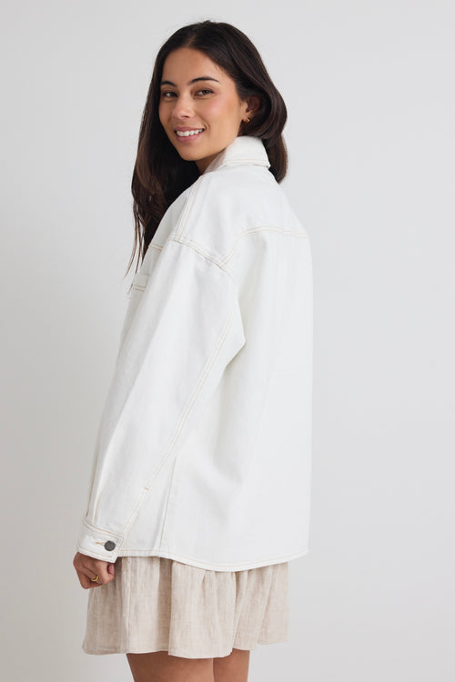 Model wears a ivory white denim jacket with front pockets and button up