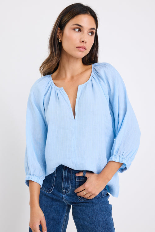 model wears a blue linen stripe blouse with dark blue jeans