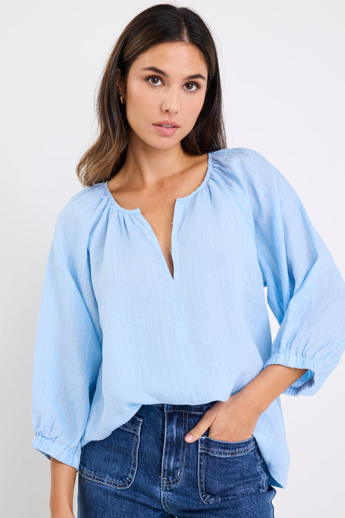 model wears a blue linen stripe blouse with dark blue jeans