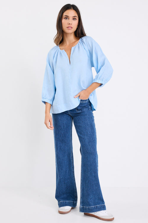 model wears a blue linen stripe blouse with dark blue jeans