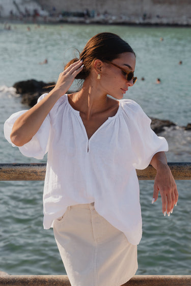 model wears white linen top and ecru mini skirt