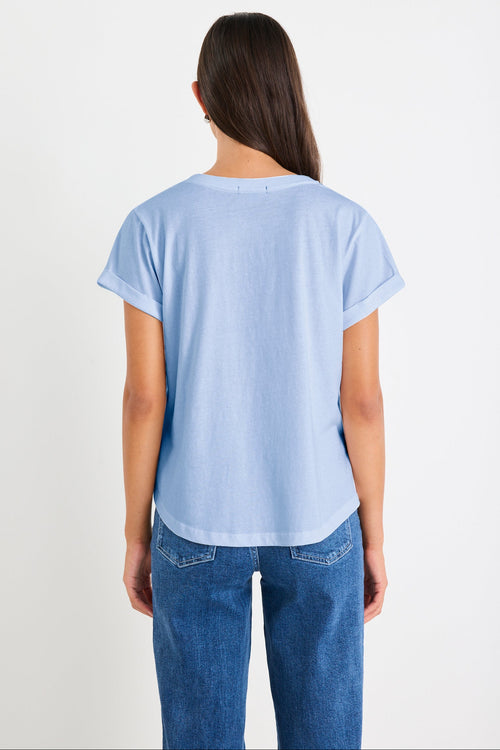 Person wearing a light blue t-shirt and blue jeans on a white background