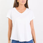 Woman wearing a white t-shirt and blue jeans on a plain background