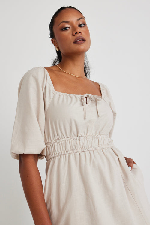 Model wears a linen  midi dress with a slit in the leg. 