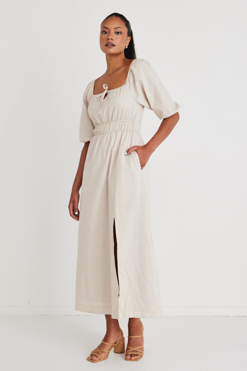 Model wears a linen  midi dress with a slit in the leg. 