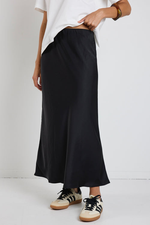 Model wears a black satin midi skirt