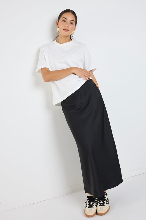 Model wears a black satin midi skirt