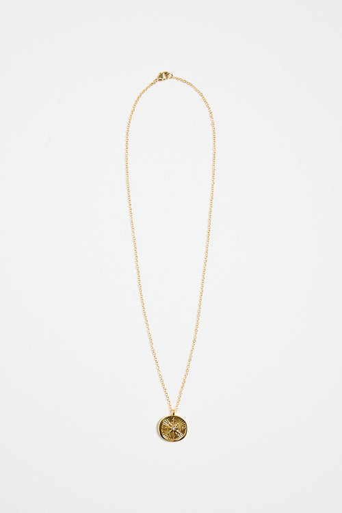 gold-plated necklace with fine chain and a round sunburst pendant featuring a central gem detail,