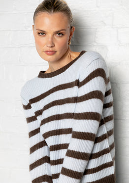 Woman wearing a brown and white striped sweater against a light background