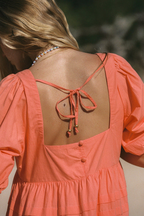 model wears a orange mini dress