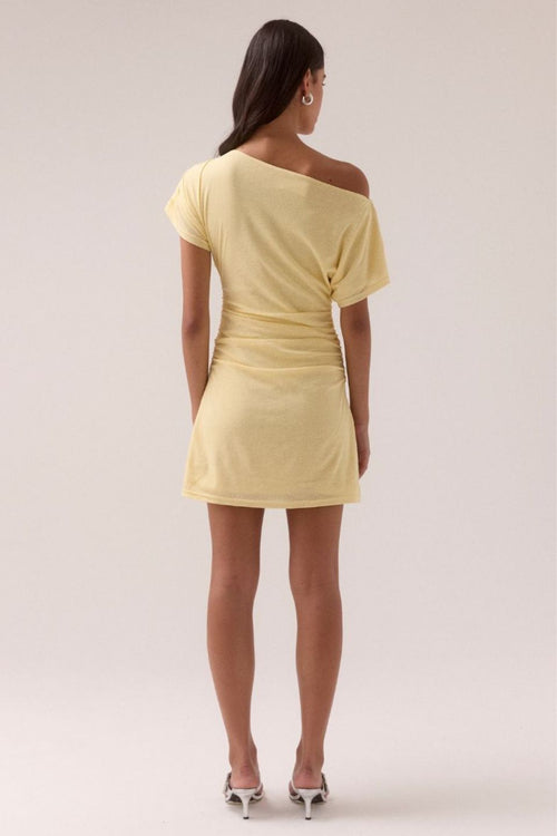 Lemon yellow off-shoulder mini dress with ruched side detailing, short draped sleeve, and fitted silhouette, worn by a model standing front-facing against a neutral background.