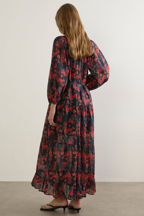 Woman wearing a long floral dress against a plain background