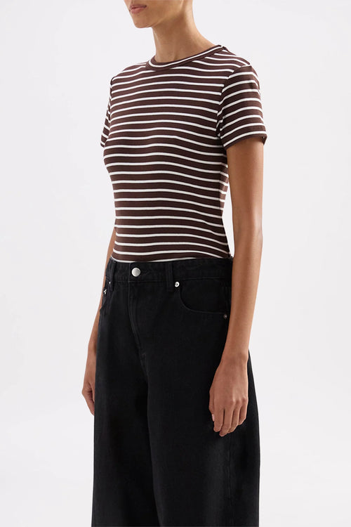 A model wearing a short-sleeve crewneck t-shirt with thin brown and white horizontal stripes, paired with black wide-leg jeans, against a plain white studio background.