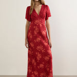 Woman wearing a red floral dress against a plain background