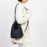 Woman carrying a black backpack against a white background