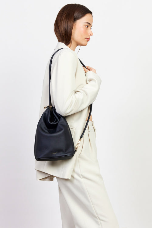 Woman carrying a black backpack against a white background
