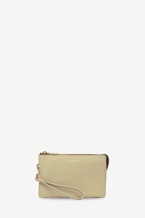 A small beige leather wristlet pouch with a matching wrist strap, gold-tone zipper and hardware, and subtle 'SABEN' branding on the front, shown against a plain white background.