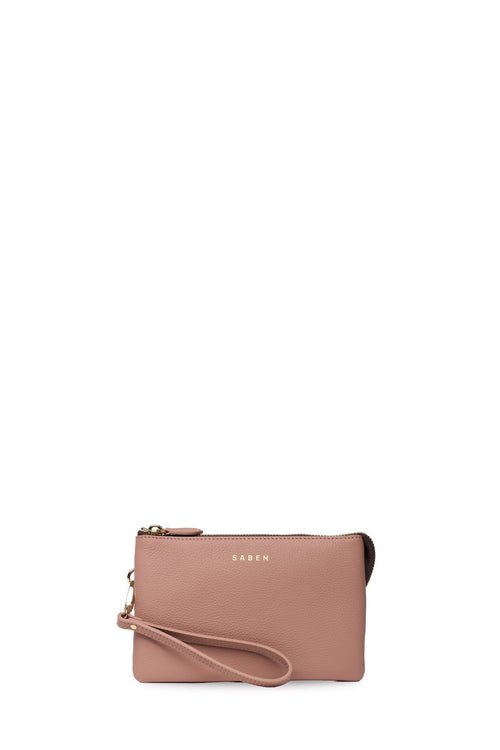 A dusty pink leather wristlet clutch with a matching wrist strap and gold-tone hardware, featuring the KAWS logo on the front, set against a plain white background.