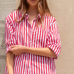 Woman wearing a red and white striped shirt against a beige wall.